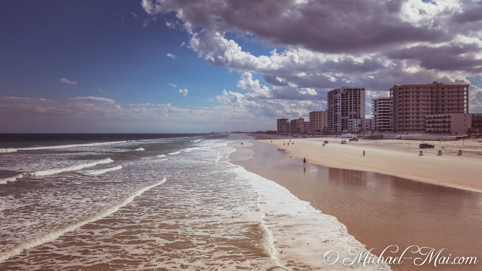 Waves crash rhythmically along the shore, mirroring the city's coastal architecture under stormy skies. | Daytona Beach Shores, Florida, United States