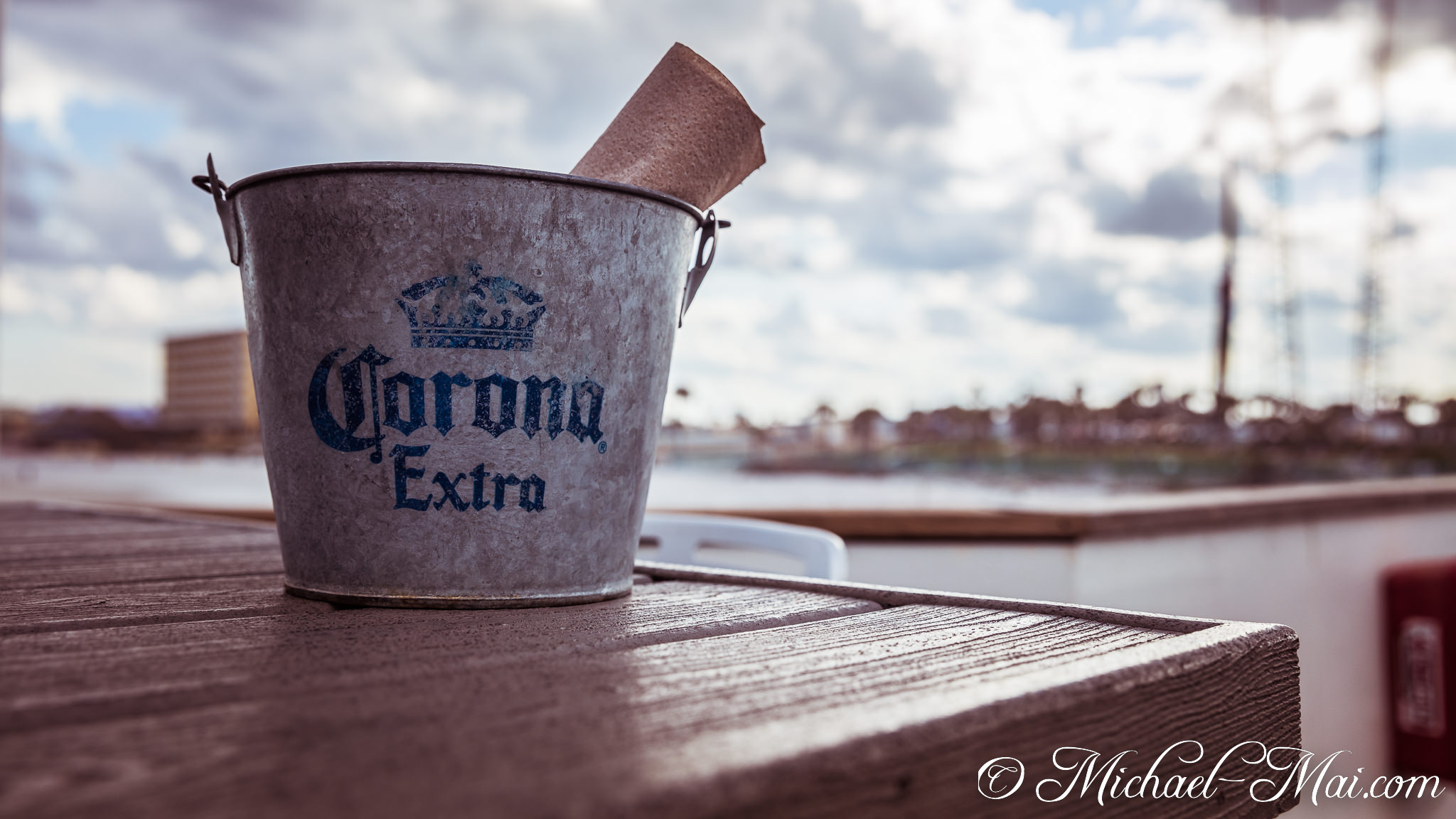 Rustic Corona Extra bucket sits on a textured wooden table with a scenic background. | Daytona Beach, Florida, United States