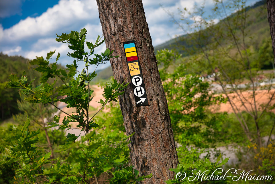 Guidepost details the Pfälzer Höhenweg, pointing onward amidst a green valley panorama. | Hauenstein, Germany