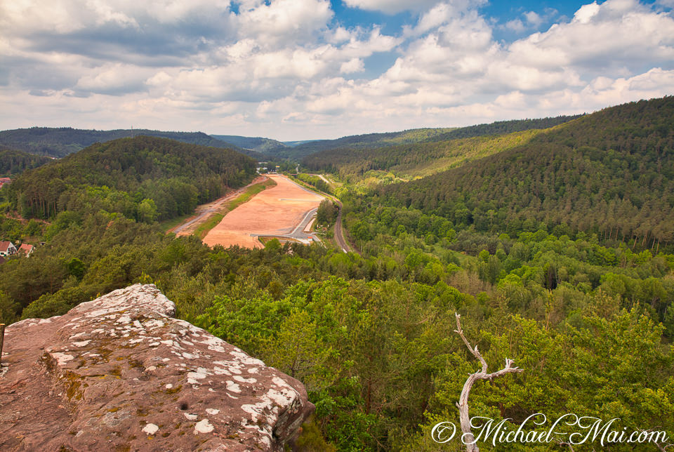 Rocky foreground frames a verdant valley, where development reshapes the forested landscape. | Hauenstein, Germany