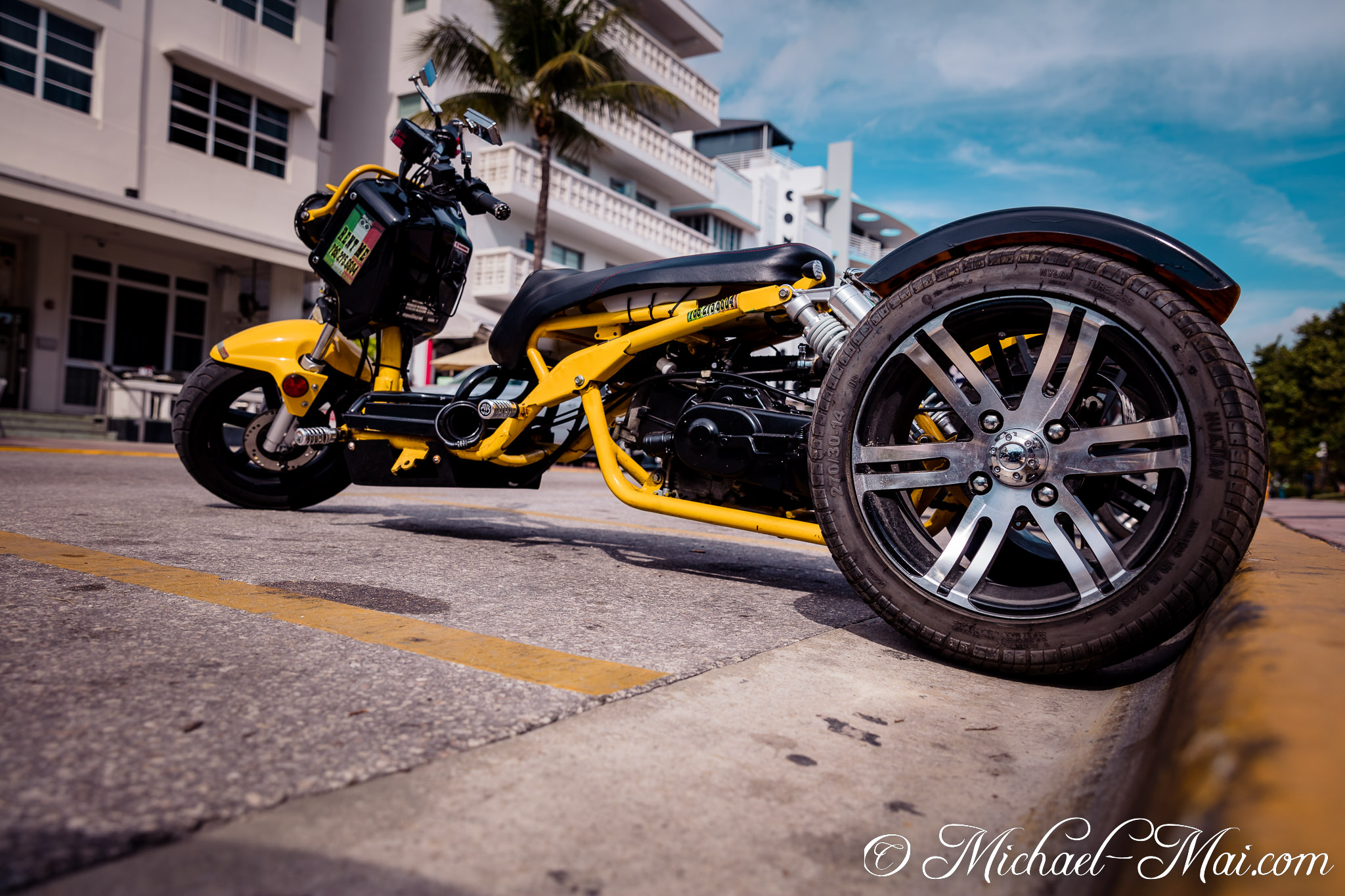 Custom yellow three-wheeled scooter detailed from a low, dynamic street perspective. | Miami Beach, Florida, United States