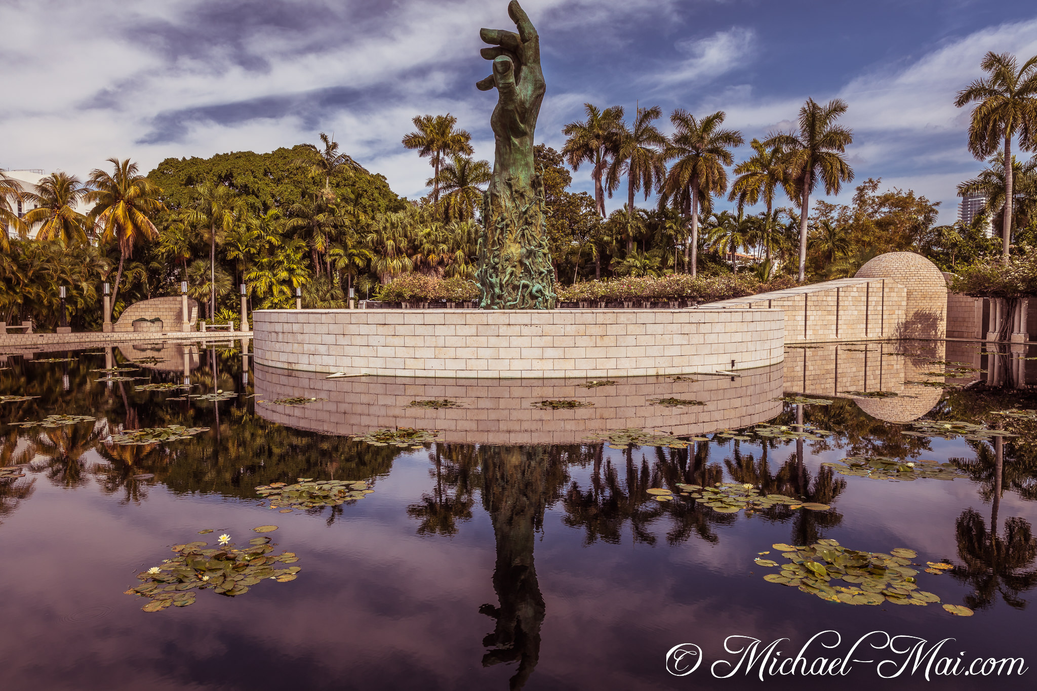 Somber bronze figures reach skyward, their reflection mirroring sorrow in still waters. | Miami Beach, Florida, United States