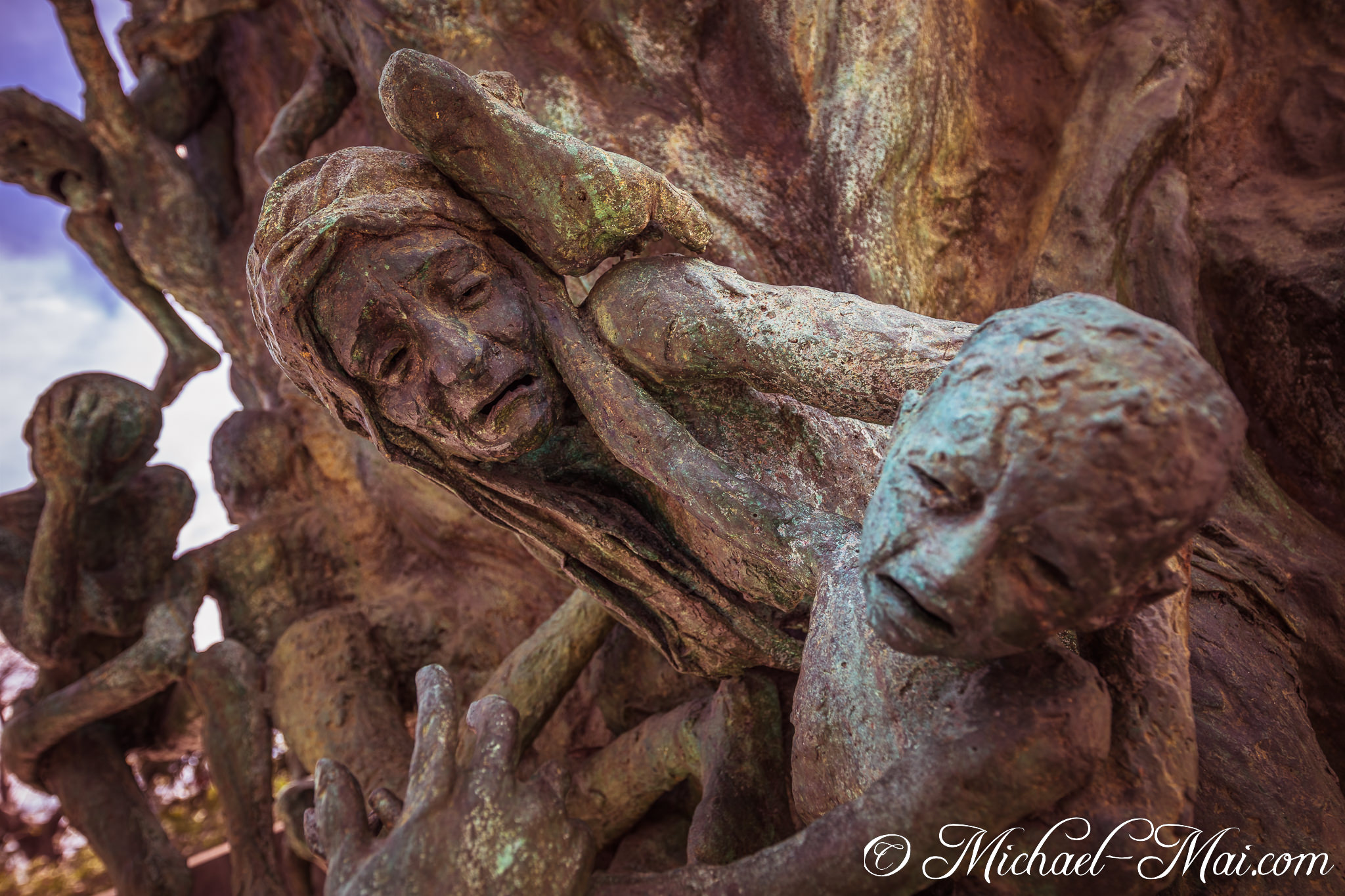 Close-up on bronze faces, eyes shut in silent anguish, amidst a tangle of forms. | Miami Beach, Florida, United States