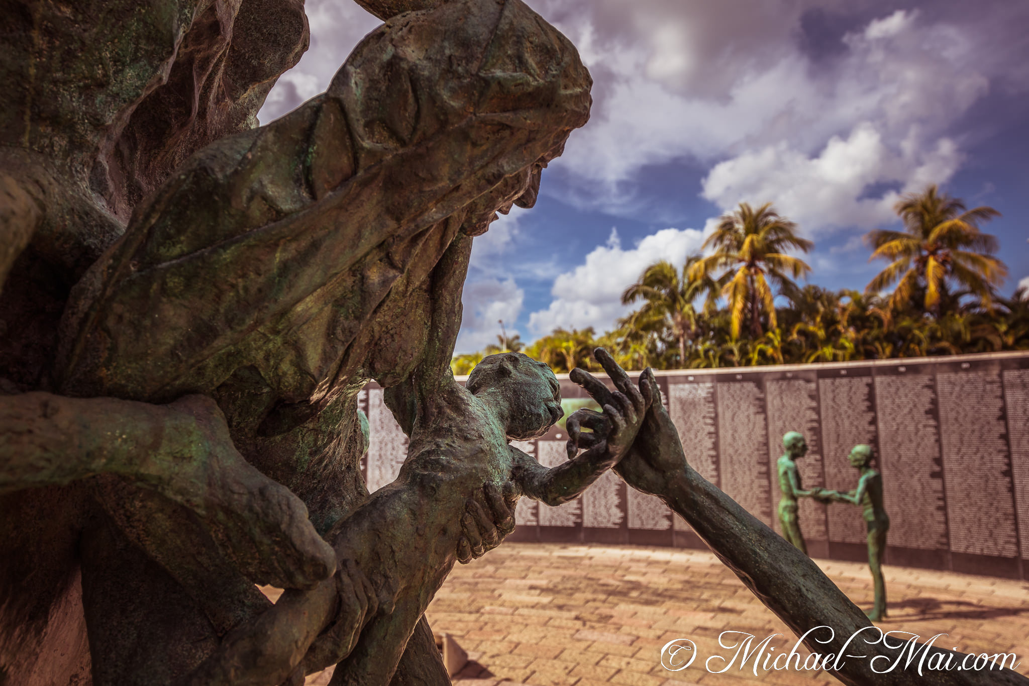Textured bronze sculpture captures a powerful, protective embrace near a veterans' memorial. | Miami Beach, Florida, United States
