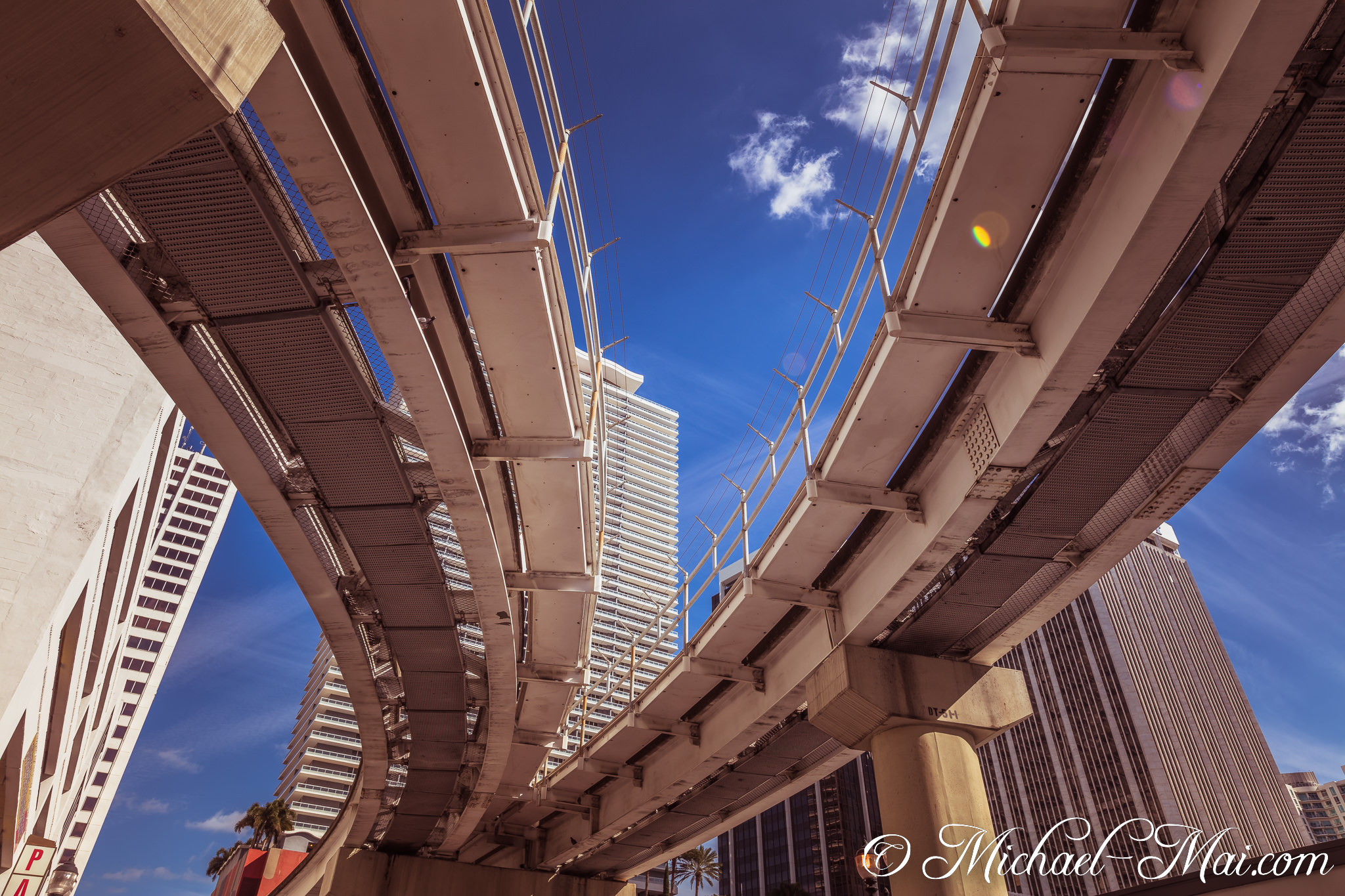 Upward gaze reveals intersecting city tracks and sun-drenched architectural forms. | Miami, Florida, United States