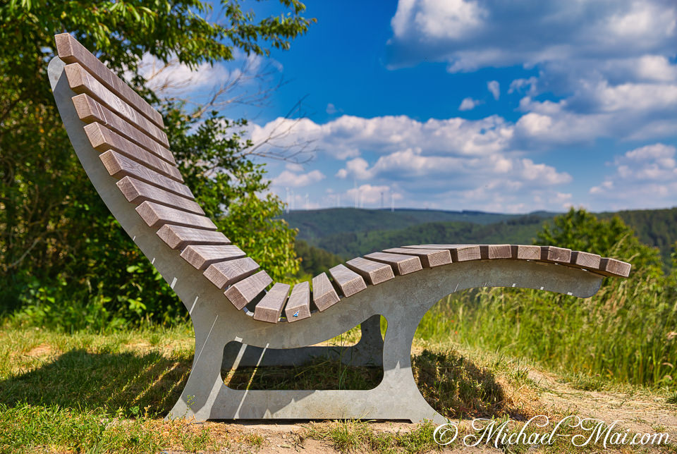 From its perch, a contemporary bench frames a panoramic vista of forested hills and wind farms.