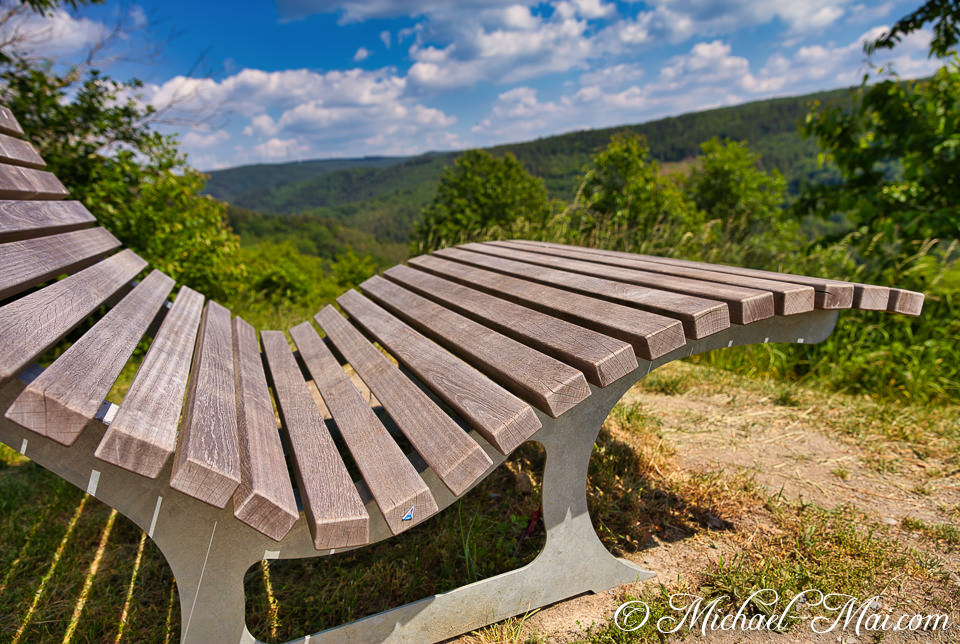 Relax on a modern bench, absorbing the vast, sunlit panorama of rolling hills.