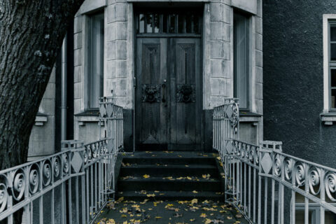 Weathered stone and bark frame a leaf-strewn path to an ornate autumn entrance.
