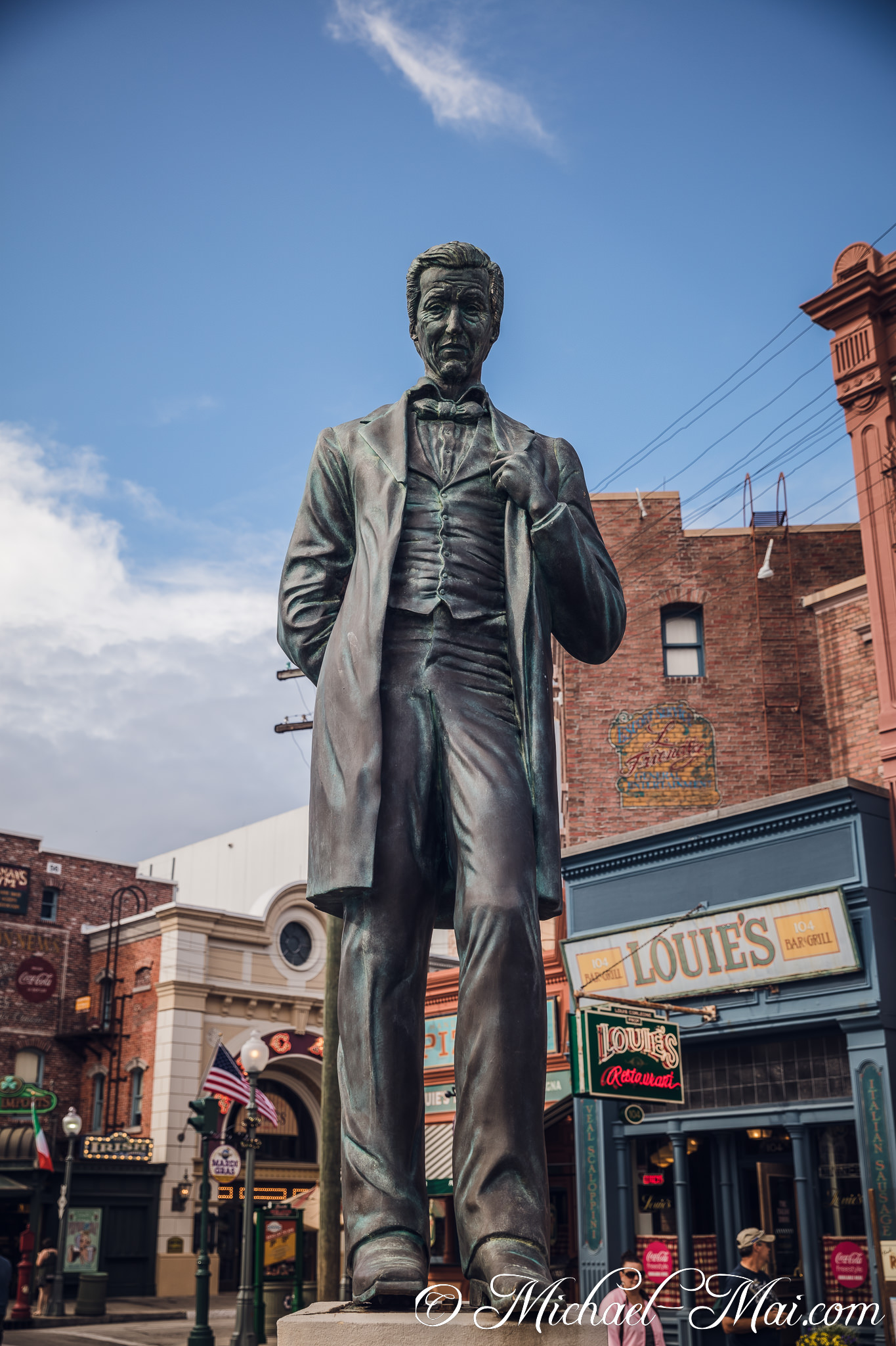 Dignified bronze statue commands attention amidst a bustling themed street scene. | Orlando, Florida, United States
