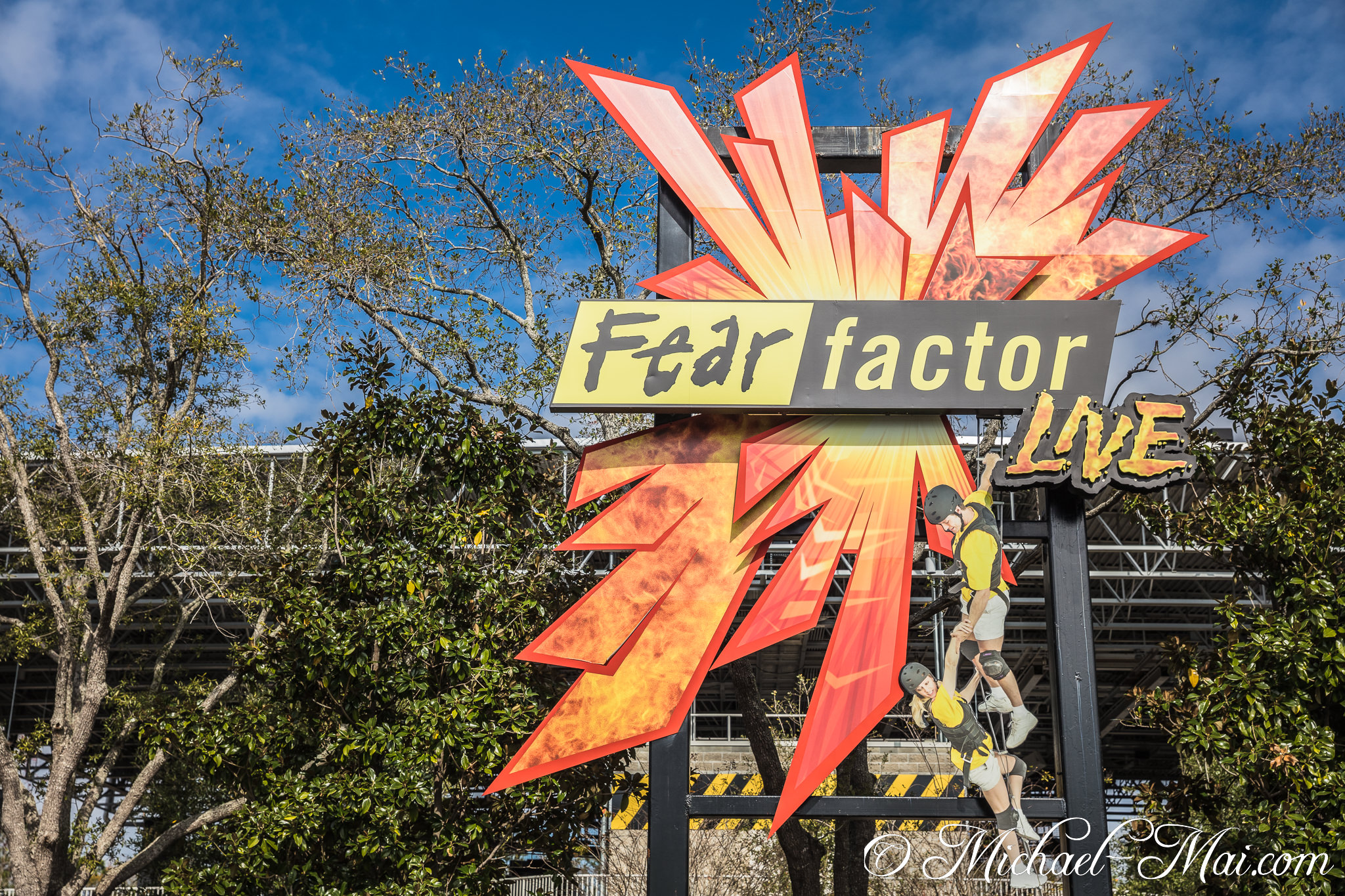 Dynamic Fear Factor LIVE sign showcases stunt figures against a vibrant sky. | Orlando, Florida, United States