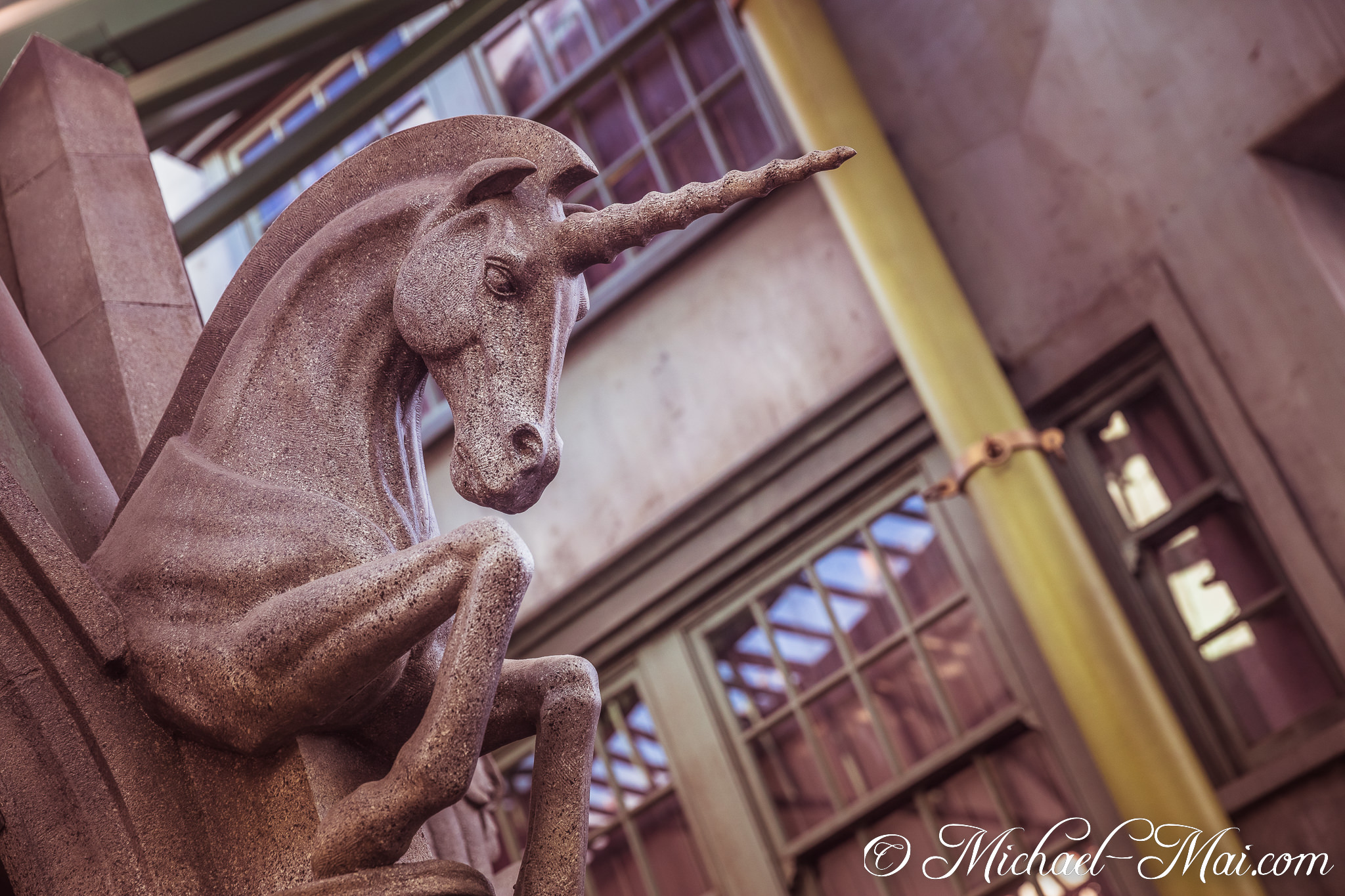 Rough-hewn stone unicorn, its distinctive horn raised, emerges from a blurred backdrop. | Orlando, Florida, United States