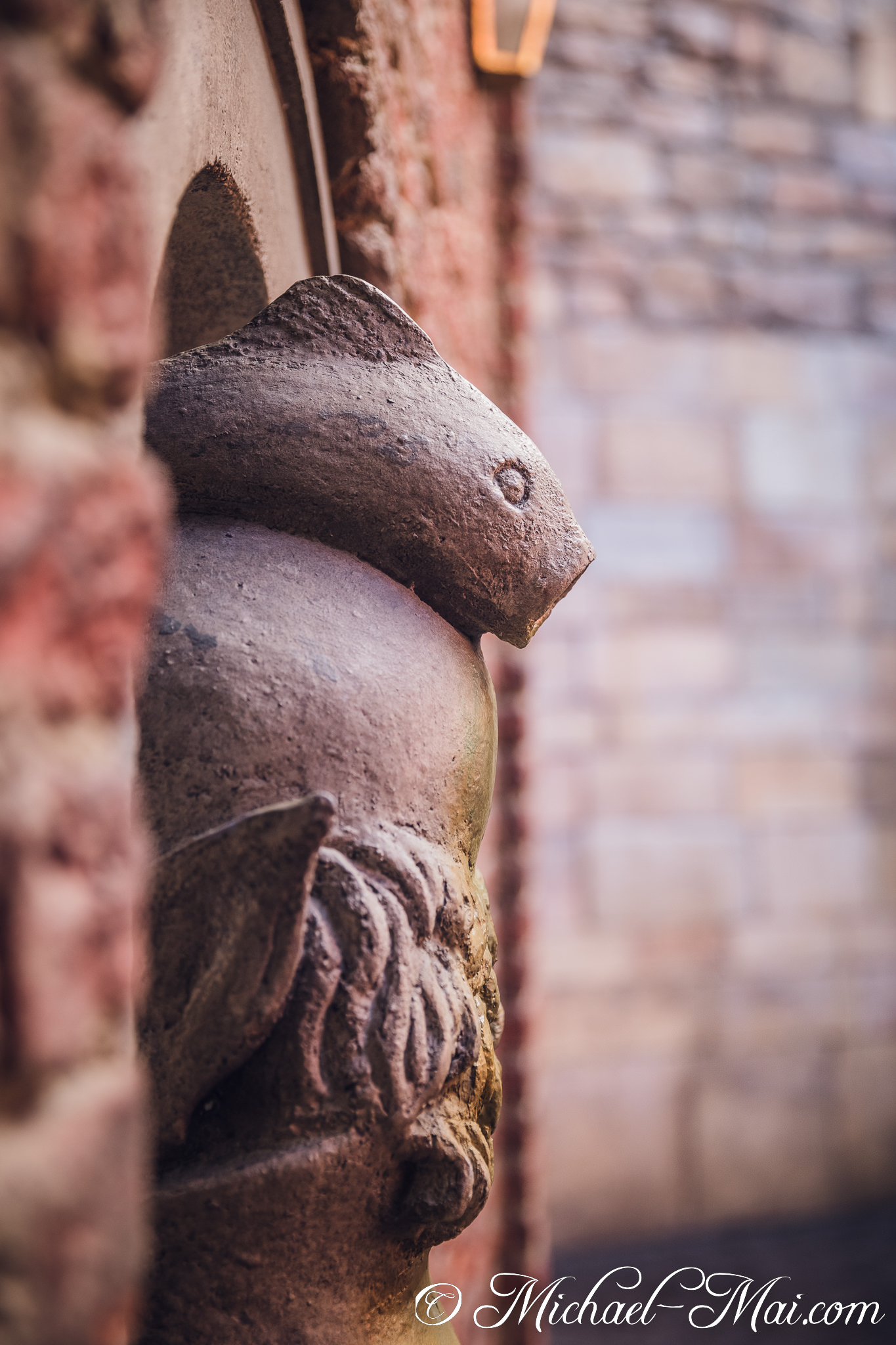 Among weathered bricks, a stone fish sculpture with a simple eye peers out. | Orlando, Florida, United States