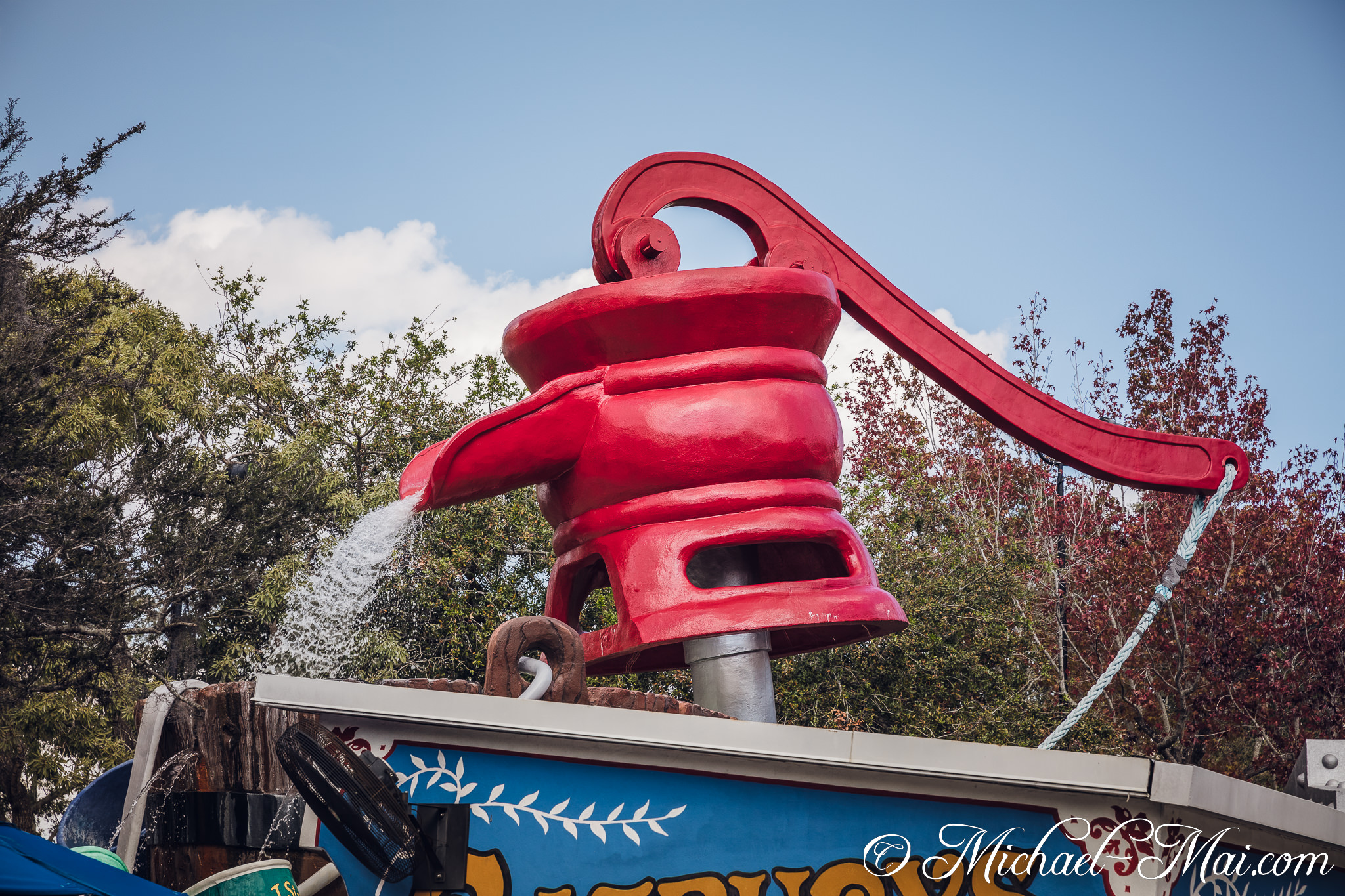 Vibrant red pump playfully streams water against a bright sky. | Orlando, Florida, United States