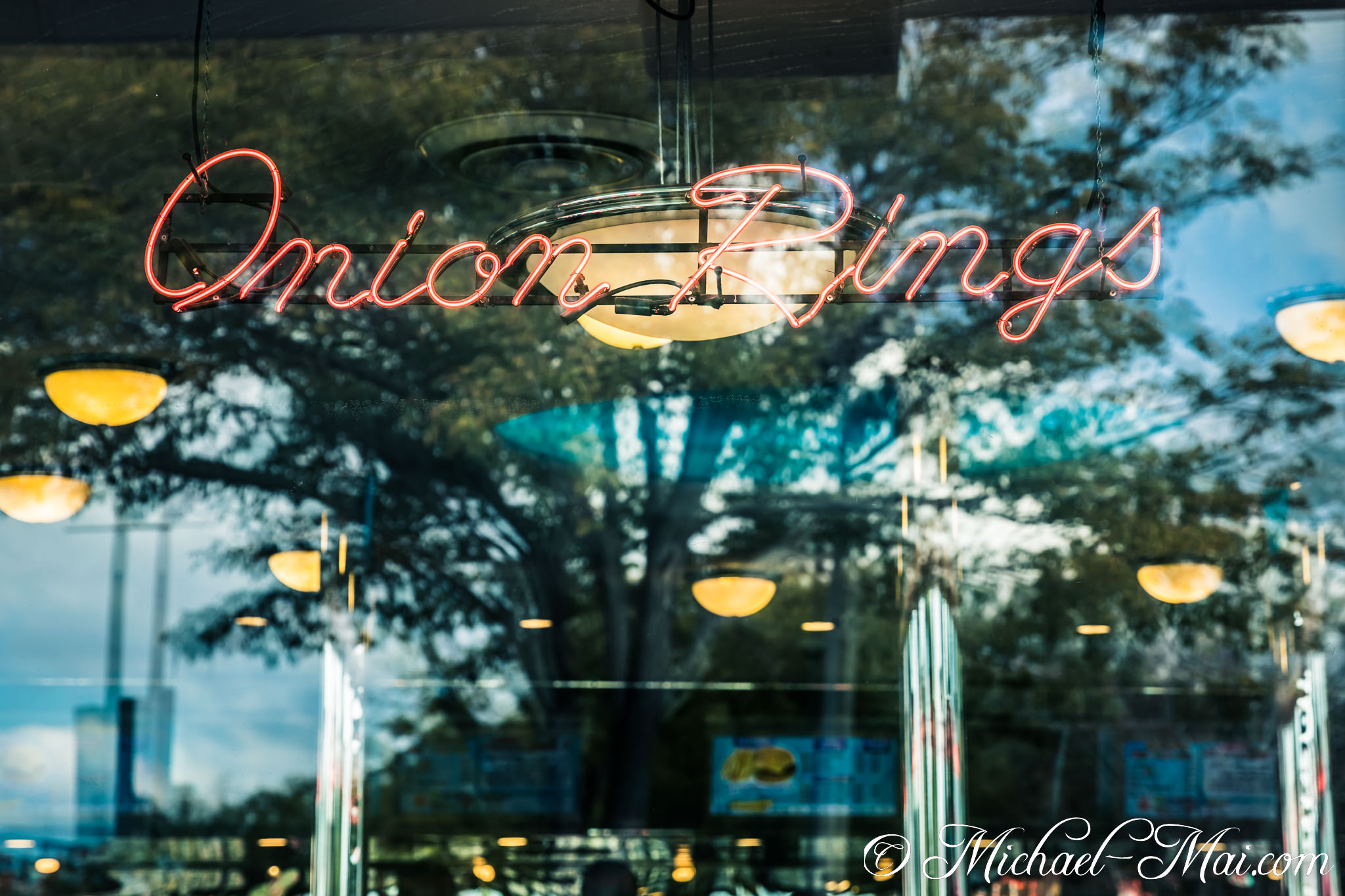 Vibrant neon "Onion Rings" sign glows with layered reflections in a diner window. | Orlando, Florida, United States