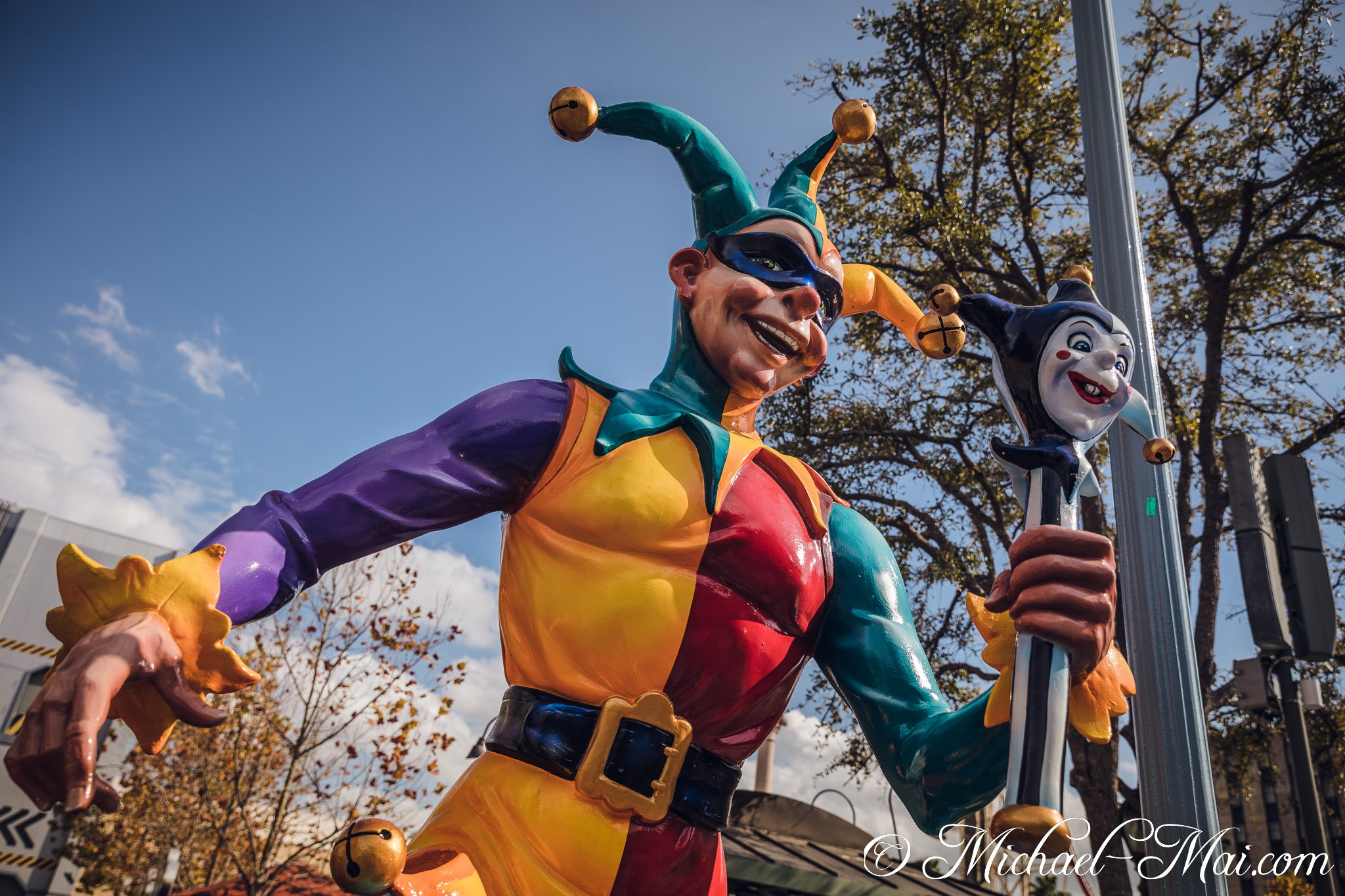 Grinning widely, a vibrant Mardi Gras jester statue greets onlookers from below. | Orlando, Florida, United States