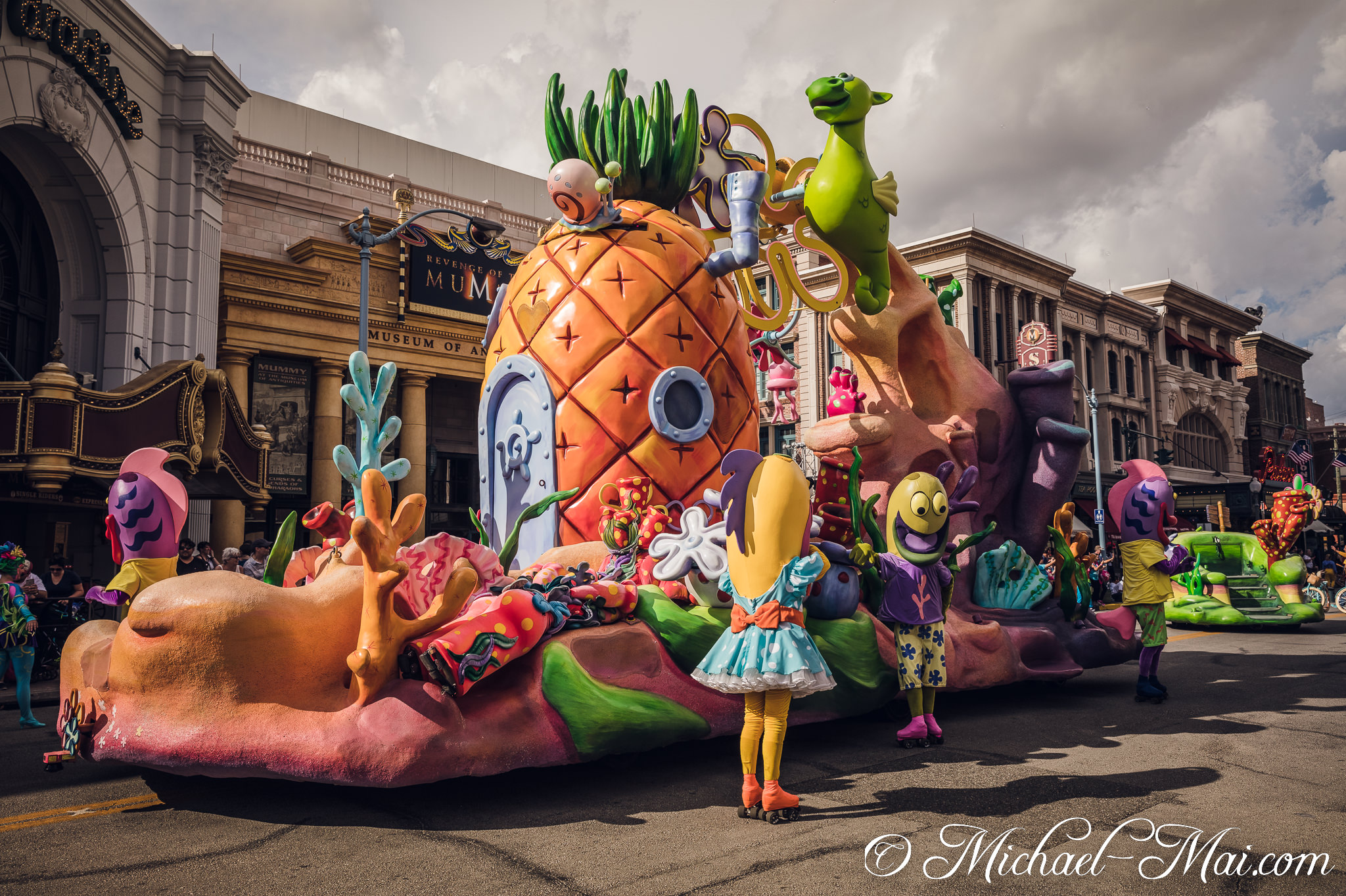 Cheerful characters and the famous pineapple house glide through a vibrant street parade. | Orlando, Florida, United States