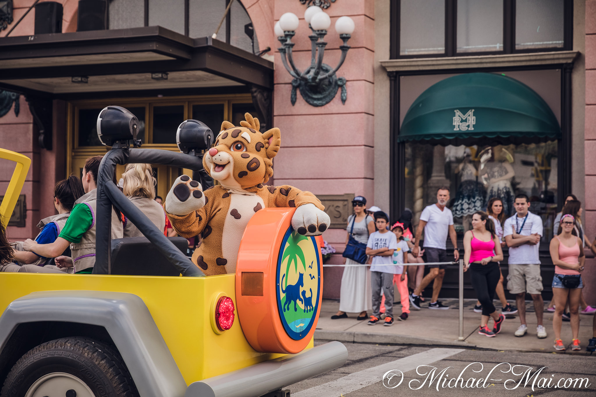 Engaging with onlookers, a spotted leopard character waves from a colorful parade vehicle. | Orlando, Florida, United States