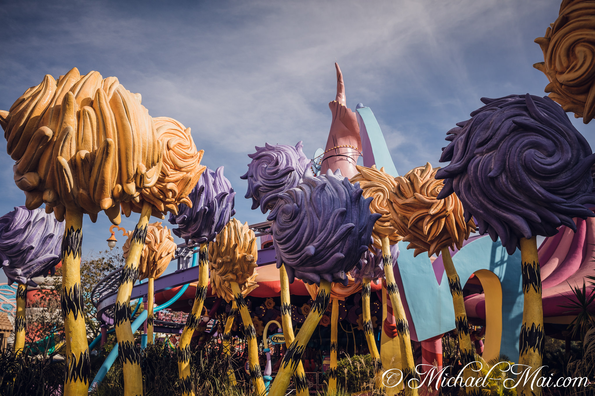 Whimsical purple and yellow Truffula trees frame a bright, imaginative theme park vista. | Orlando, Florida, United States