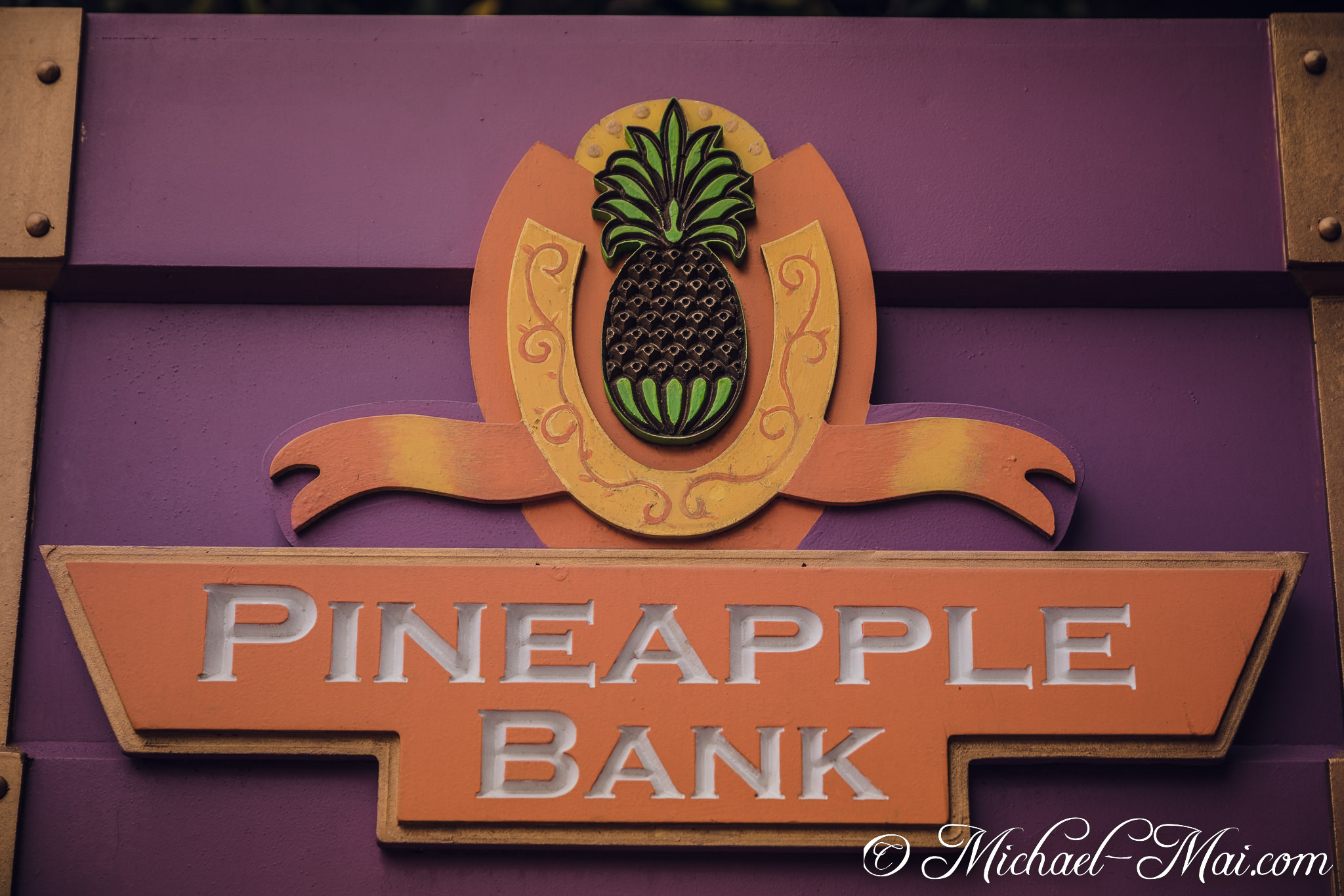 Carved pineapple emblem decorates the lively "Pineapple Bank" sign in bright hues. | Orlando, Florida, United States